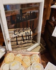 some cookies are sitting in a box on the table next to an old fashioned window