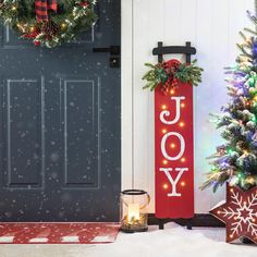 two christmas wreaths are next to a door with the word joy written on it