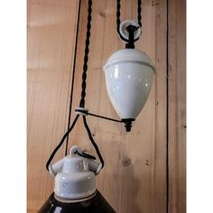 an old fashioned lamp hanging from the side of a wooden wall next to a hook