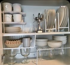 dishes and glasses are stacked on shelves in the kitchen