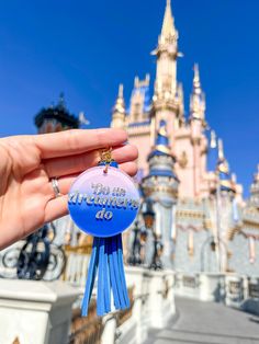 someone holding up a disney world ornament in front of the castle at disneyland