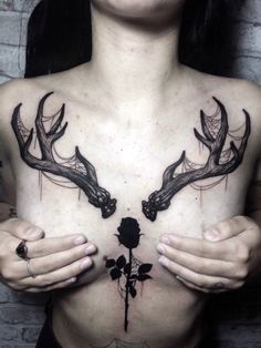 a woman holding her chest with two deer antlers on it and a rose in the middle