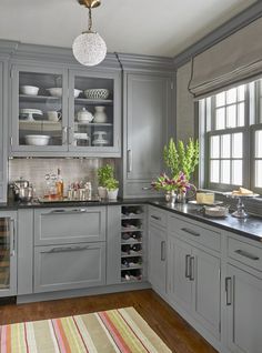 a kitchen filled with lots of gray cabinets and counter top space next to a window