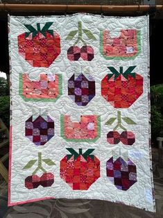 a quilted wall hanging on the side of a building with strawberries and cherries