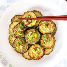 a white plate topped with cucumbers and chopsticks