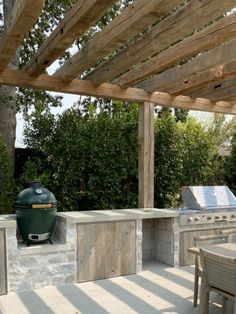 an outdoor kitchen with grill, table and chairs