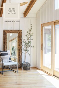 a living room with white walls and wood flooring, a large mirror on the wall