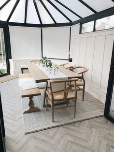 a dining room table with chairs and a vase on top of it in front of a glass wall