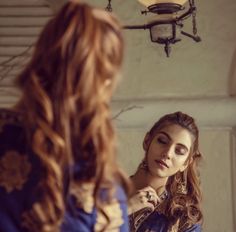 a woman is straightening her hair in front of a mirror