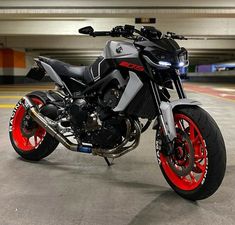 a motorcycle is parked in an empty parking garage with red rims on the tires