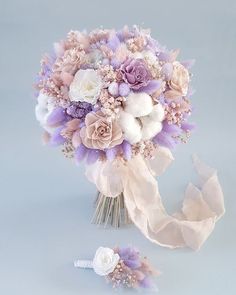 a bridal bouquet with purple and white flowers on it next to a hair comb