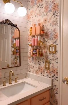 a bathroom with floral wallpaper and gold faucets on the mirror above the sink