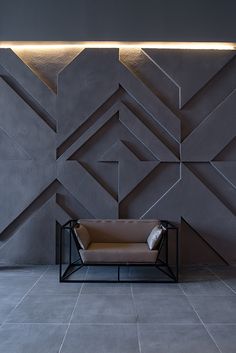 a chair sitting on top of a tiled floor next to a wall covered in geometric shapes