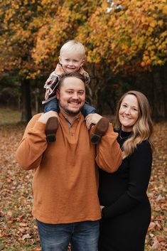 a man, woman and child are posing for a photo in the fall with leaves on the ground