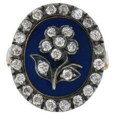 an antique blue and white enamel flower ring with diamonds in the center on a white background