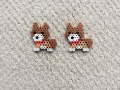 two brown and white dog shaped earrings sitting on top of a carpet next to each other