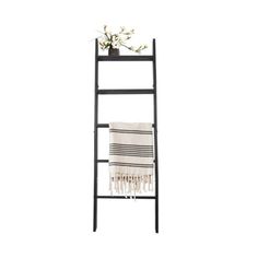 a black ladder shelf with a white towel and flowers on top, against a white background