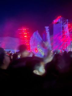 the crowd is watching an outdoor concert with bright lights on stage and in front of them