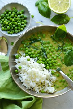 peas, rice and spinach in a bowl on a table with spoons next to it