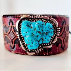 An exquisite sterling turquoise brooch handmade by Navajo artisan L. Smith features a rugged chunk of brilliant blue Kingman turquoise surrounded by a carved platform of sterling silver and paired with a spectacular vintage hand tooled leather belt to be repurposed into a leather bracelet. A deerskin lace wraps around a genuine Indian Head buffalo nickel concho for a comfortable, secure and adjustable tie-on closure. Rustic Concho Jewelry For Western-themed Events, Handmade Turquoise Jewelry For Western-themed Events, Rustic Turquoise Concho Jewelry, Vintage Turquoise Concho Cuff Bracelet, Western Style Turquoise Bracelet, Hand Tooled, Vintage Turquoise Cuff Bracelet With Concho, Southwestern Silver Leather Jewelry, Southwestern Hand Tooled Leather Bracelets, Turquoise Concho Cuff Bracelet Gift