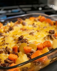 a casserole dish with meat, potatoes and carrots in it on the stove