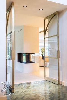 an open door leading to a living room with a fireplace in the corner and tiled floor