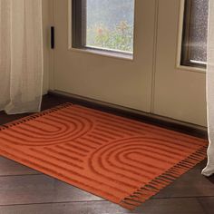 an orange rug on the floor in front of a door with curtains and window sill