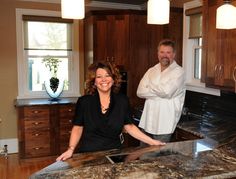 two people standing in a kitchen with granite counter tops