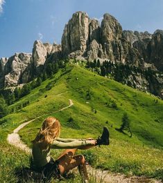 a woman sitting on top of a lush green hillside