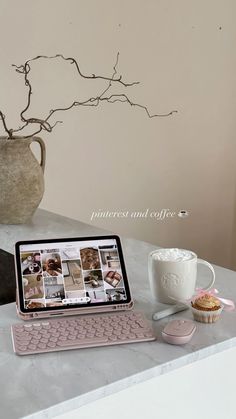 a laptop computer sitting on top of a white counter next to a cup and vase