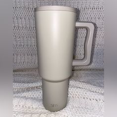 a white coffee cup sitting on top of a table next to a gray mug holder