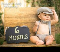 a baby sitting on top of a wooden bench next to a sign that says 6 months