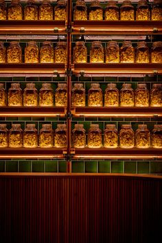 the shelves are full of baked goods in glass jars on wooden racks, with lights shining through them