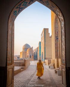 a woman in yellow dress walking through an archway