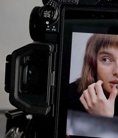 a camera with a woman's face on the screen and an electronic device in front of it