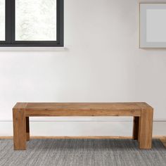 a wooden bench sitting in the middle of a living room next to a large window