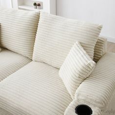 a white couch with two pillows on top of it and a black hole in the middle