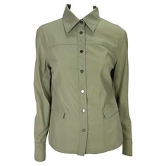 Presenting a khaki button-down collar Gucci shirt, designed by Tom Ford. From the Spring/Summer 1999 collection, this sample top was never massed produced making it the perfect rare piece for any Gucci by Tom Ford lover. A simplified safari-style shirt, this top features branded silver tone snap buttons at the front closure and cuffs and is made complete with discrete pockets at the front. Add this rare sample to your collection or wardrobe! Approximate measurements: Size - IT42 24" shoulder to Gucci Collared Cotton Tops, Gucci Cotton Collared Top, Vintage Khaki Shirt With Button Closure, Luxury Gucci Button-up Tops, Gucci Cotton Button-up Tops, Gucci Shirt, Pocket Blouse, Ford Logo, Flared Sleeves Top