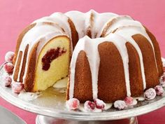 a bundt cake with white icing and cranberry toppings on a silver platter