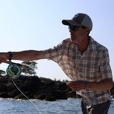 a man is holding something in his hand near the water