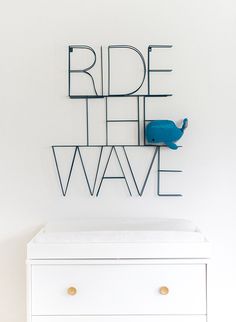 a white dresser with a blue whale on the top and words ride the wave above it