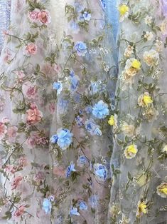 two sheer curtains with flowers on them and one has blue, pink, yellow and white