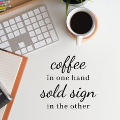 coffee in one hand sold sign in the other on a desk next to a keyboard