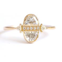 a yellow gold ring with an oval cut diamond surrounded by smaller round diamonds on the band