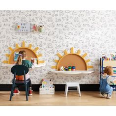 two children sitting on chairs in front of a wall with sun shaped mirrors above them