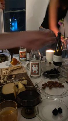 a table topped with plates and bottles of wine next to food on top of a counter