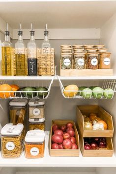 an organized pantry filled with lots of food and condiments, including apples, oranges, onions, carrots