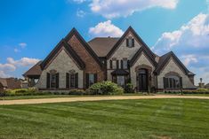 a large brick house sitting on top of a lush green field