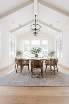 a dining room with white walls and wooden floors, an oval table surrounded by wicker chairs