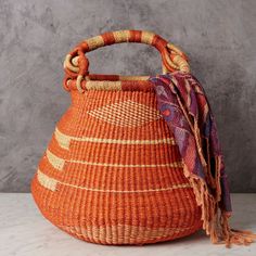 an orange woven basket sitting on top of a white counter next to a gray wall